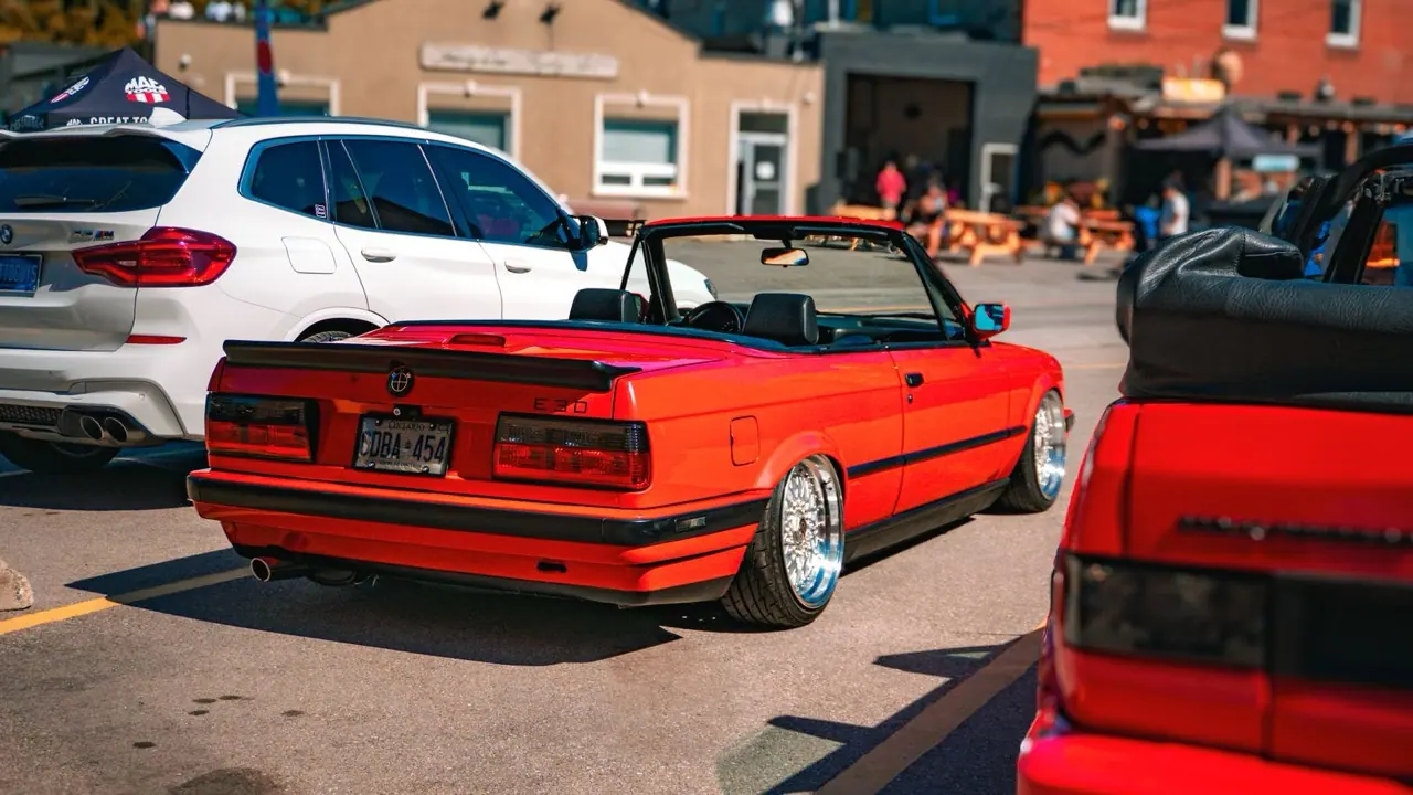 A red convertible with the top down parked on a city street