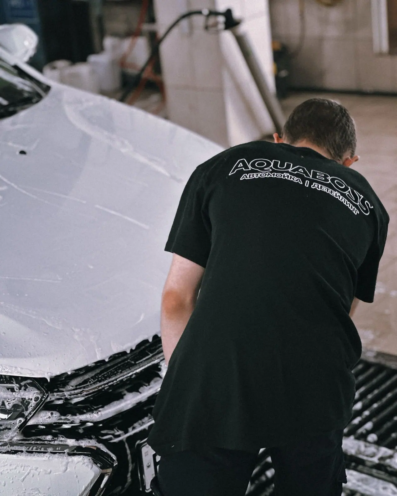 A detailer working on a white car inside a garage