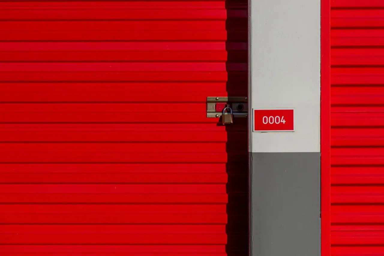A red roll-up storage unit door with a numbered tag