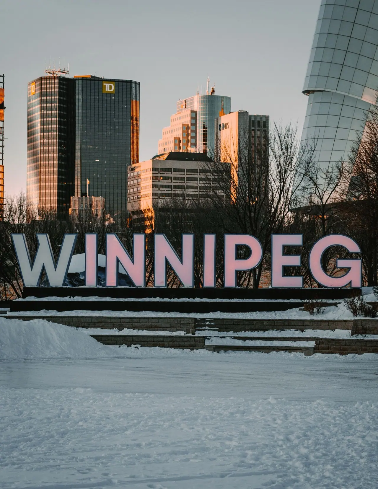 The Winnipeg sign in snow with downtown towers behind